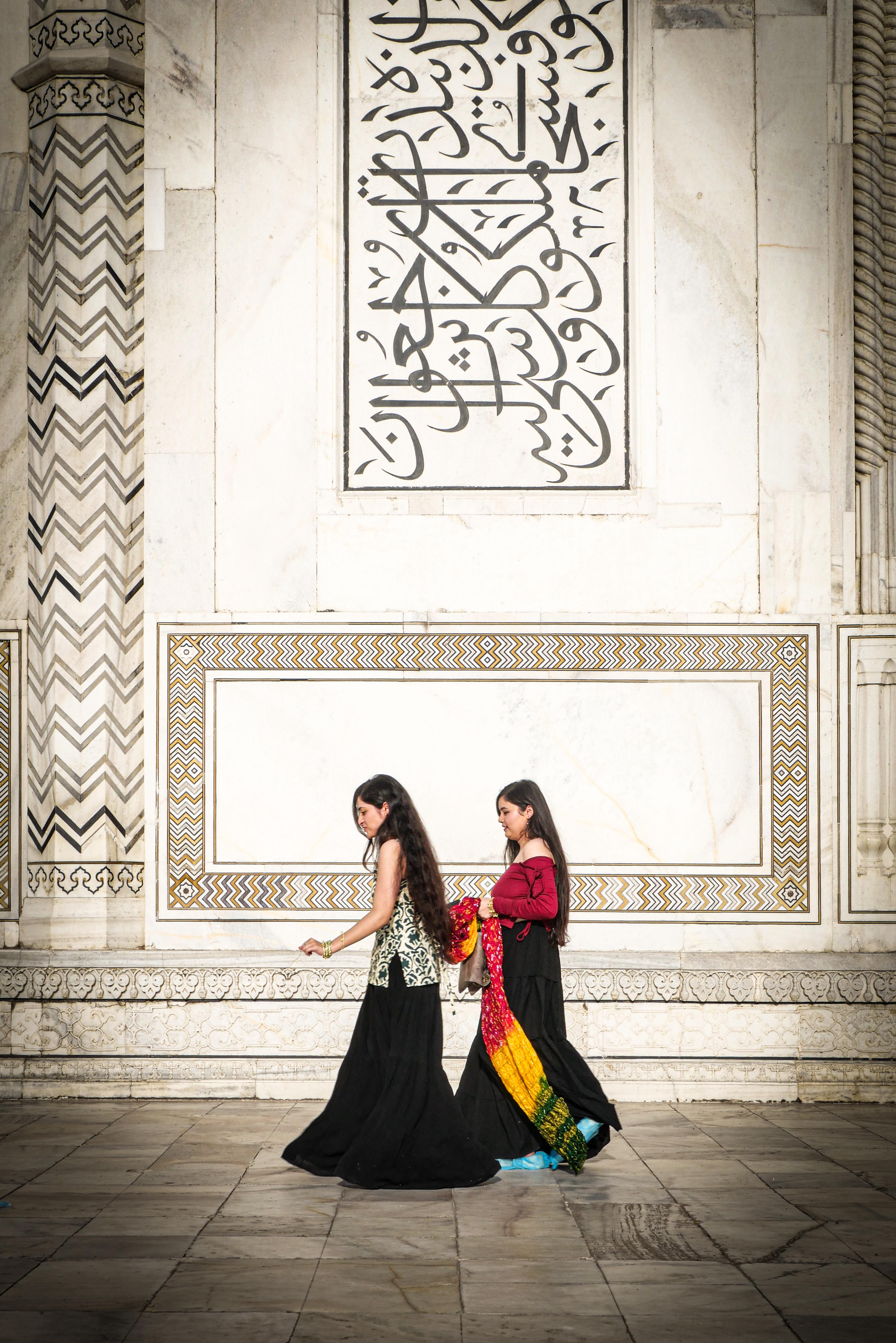 Women travellers posing in front of the white marble Taj Mahal